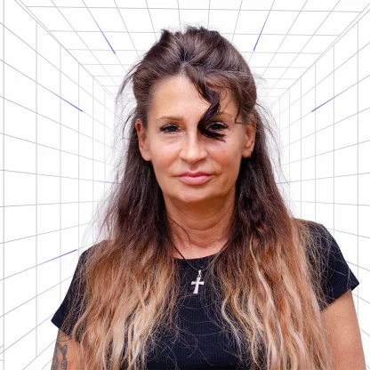 Portrait of a woman with long wavy brown hair, wearing a black shirt and a cross necklace, against a white grid background.